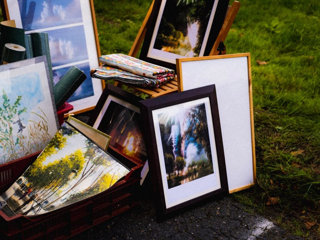 Various framed artworks displayed on grass, creating an outdoor art gallery vibe.