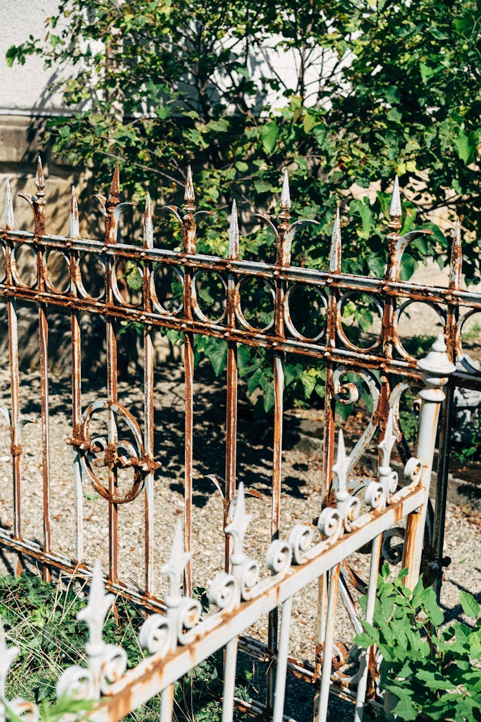 Close-up of a decorative rusty metal garden fence on a sunny day.